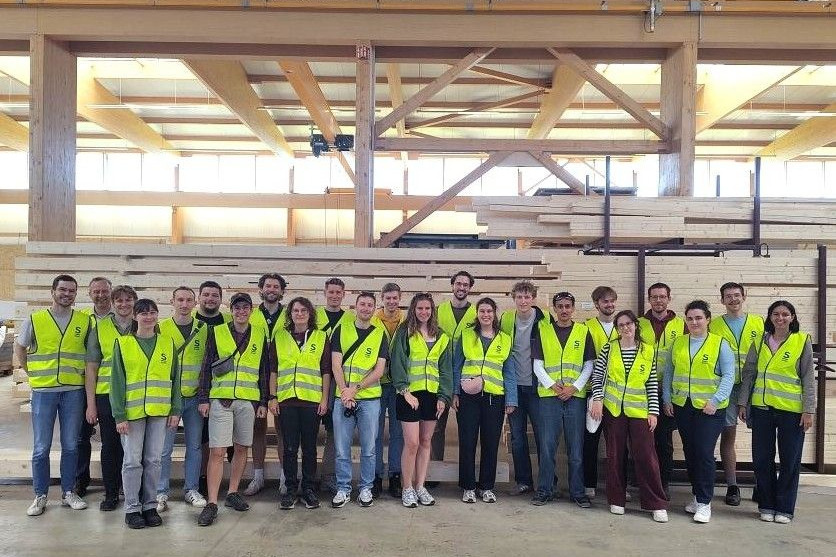Gruppe von Menschen in gelben Sicherheitswesten in einer Industriehalle.